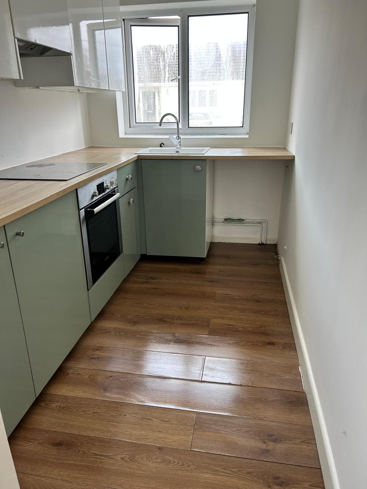 White kitchen with black worktop and integrated oven, cleaned